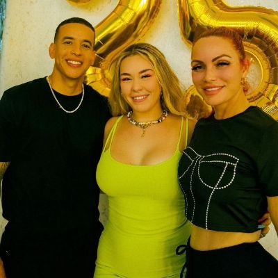 Jesaaelys Ayala González is wearing a green dress as she is standing in the middle of Daddy Yankee and Mireddys González